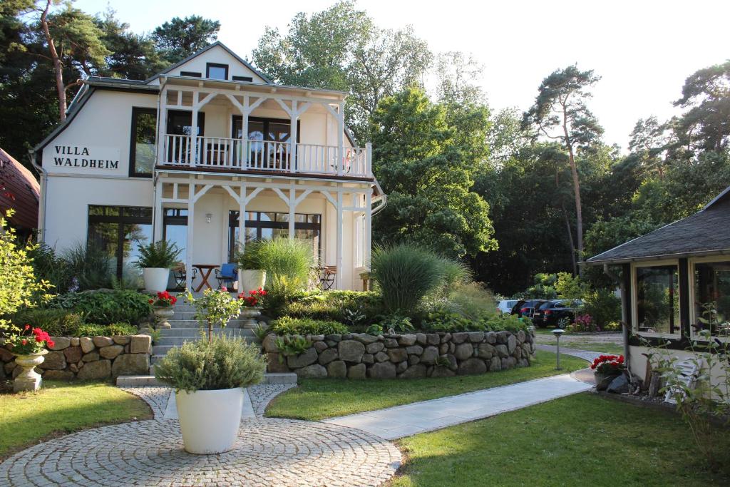 a house with a porch and a stone wall at Villa Waldheim - WG 3 in Boltenhagen