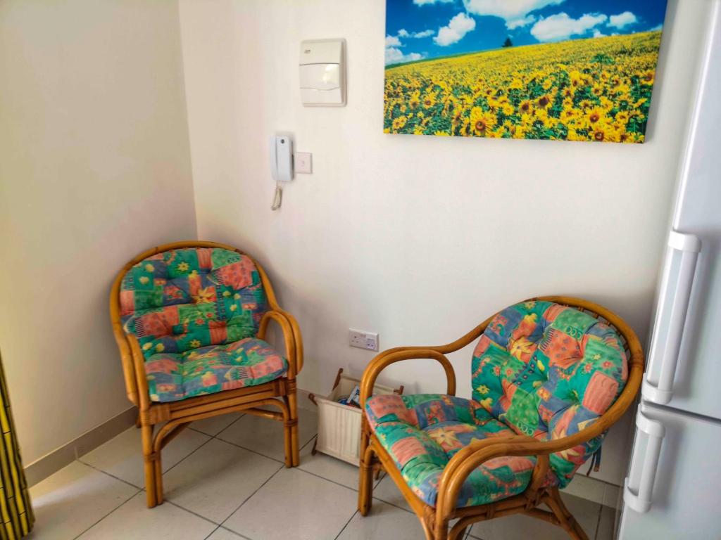 two chairs in a room with a painting on the wall at All Nations Holiday Home in Għajnsielem