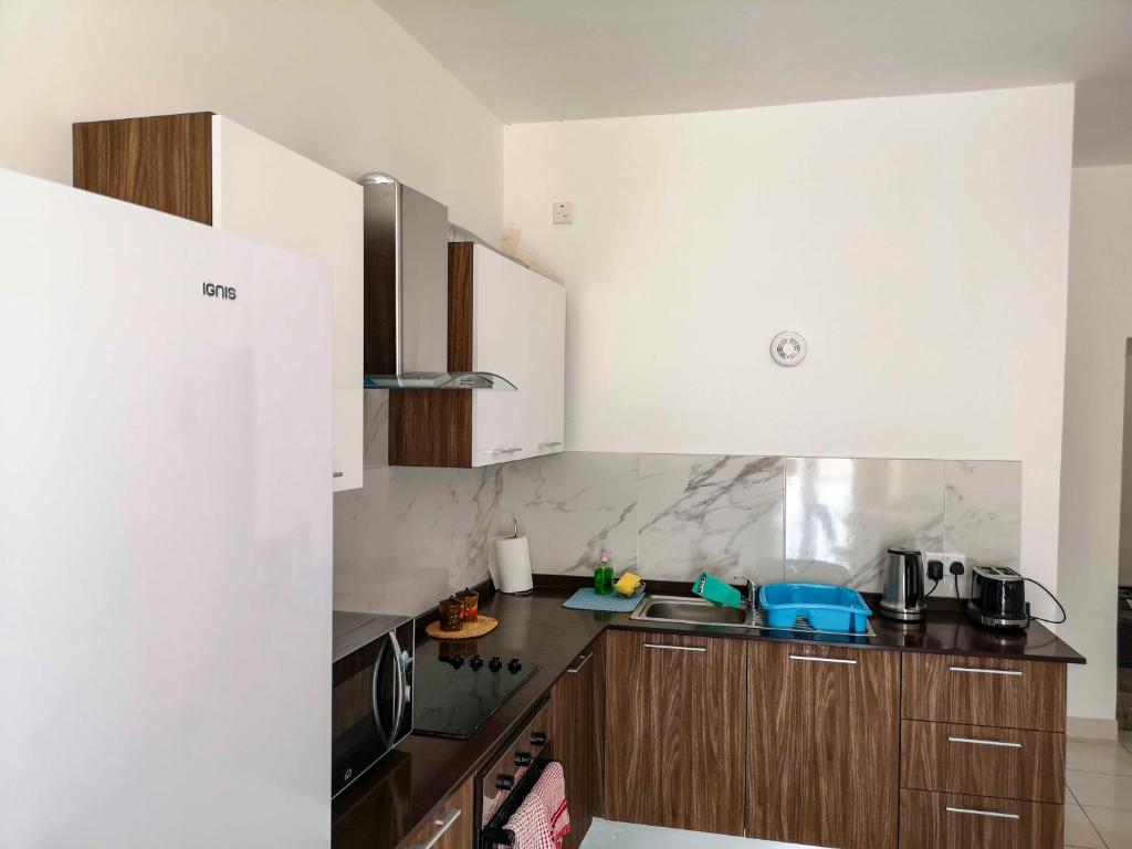 a kitchen with white cabinets and a black counter top at All Nations Holiday Home in Għajnsielem