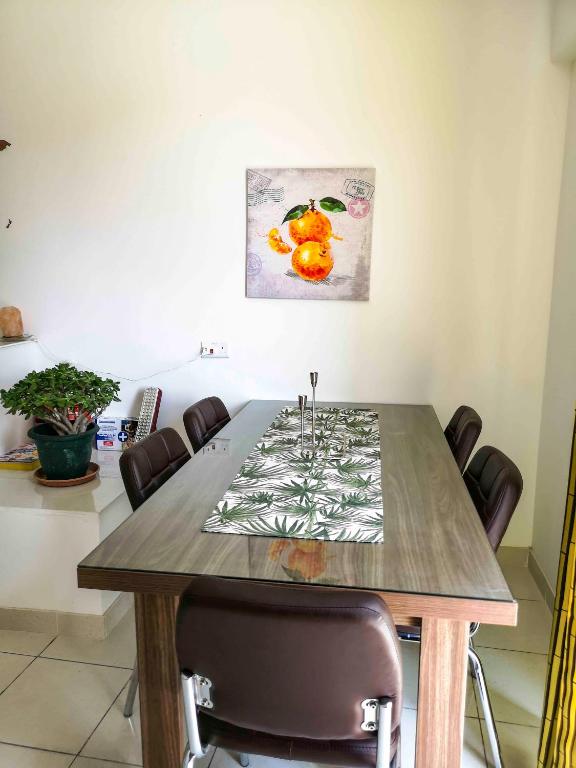 a dining room table with chairs and a painting on the wall at All Nations Holiday Home in Għajnsielem