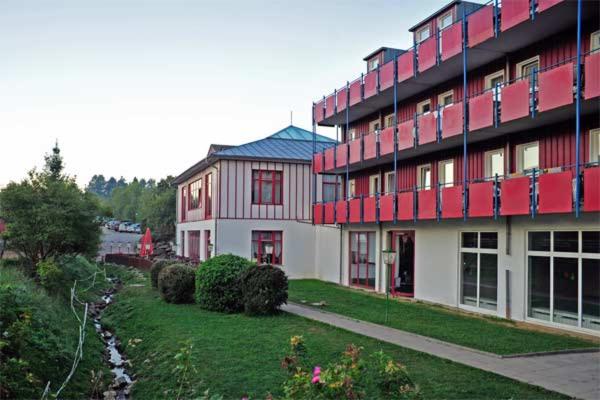 duży budynek z czerwonymi akcentami obok podwórza w obiekcie Familienhotel Reiterhof Runding w mieście Runding