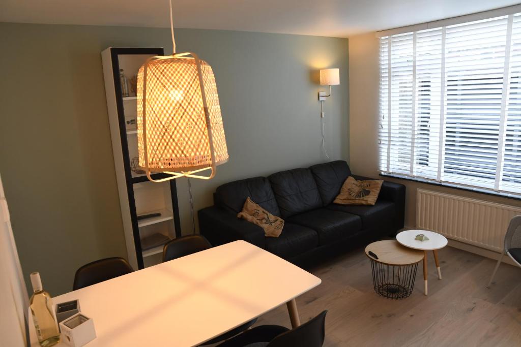 ein Wohnzimmer mit einem schwarzen Sofa und einem Tisch in der Unterkunft Bleyendaal aan Zee in Egmond aan Zee
