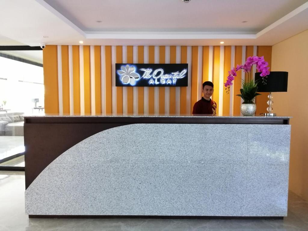 a man standing behind a reception desk in a lobby at PROXY by The Oriental Albay in Legazpi