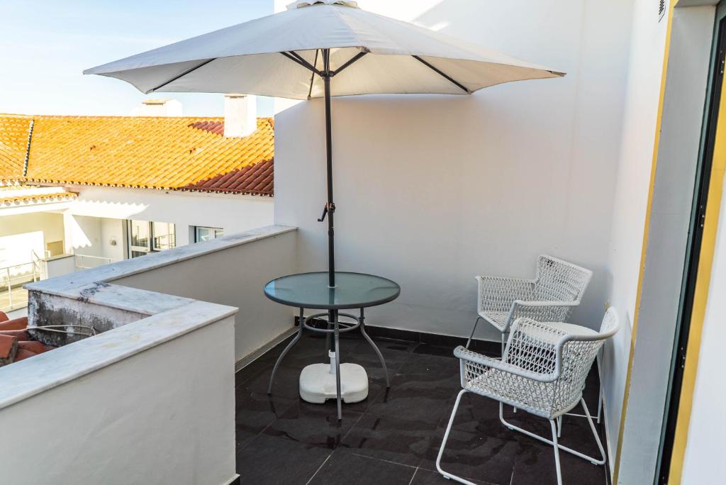 eine Terrasse mit einem Tisch, Stühlen und einem Sonnenschirm in der Unterkunft Casa do Pateo II in Évora