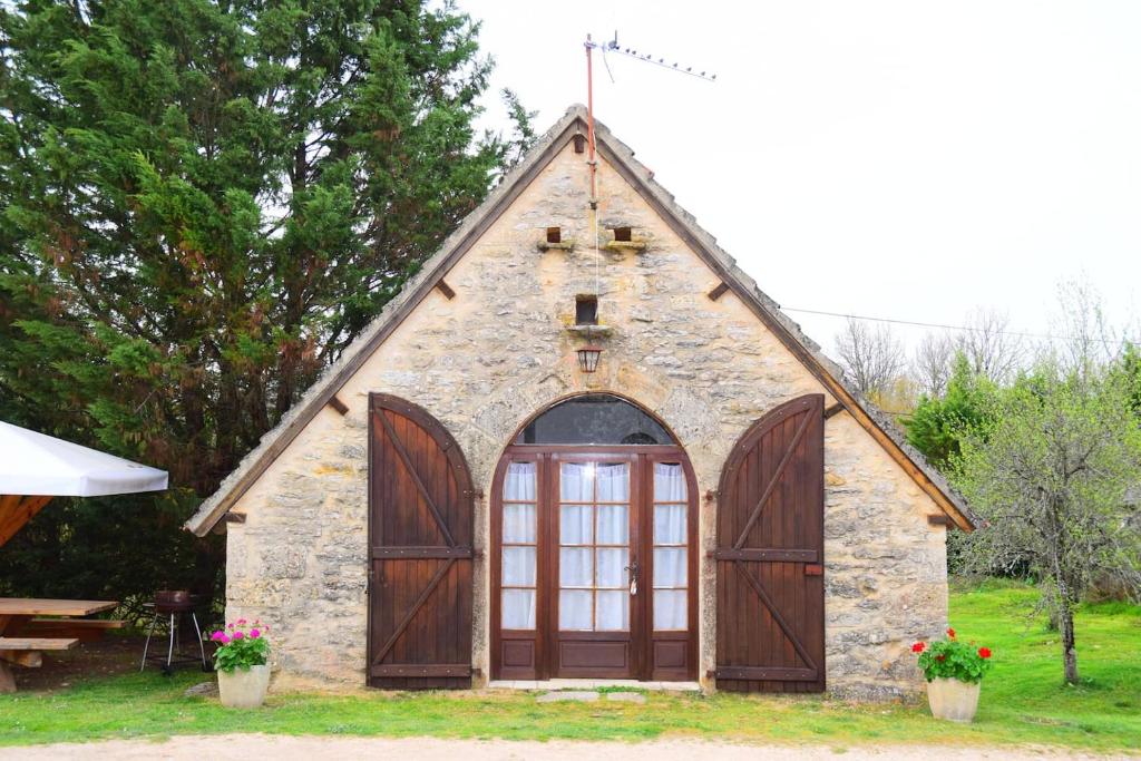 una piccola chiesa in pietra con una grande porta di grange typique du quercy a La Bécade