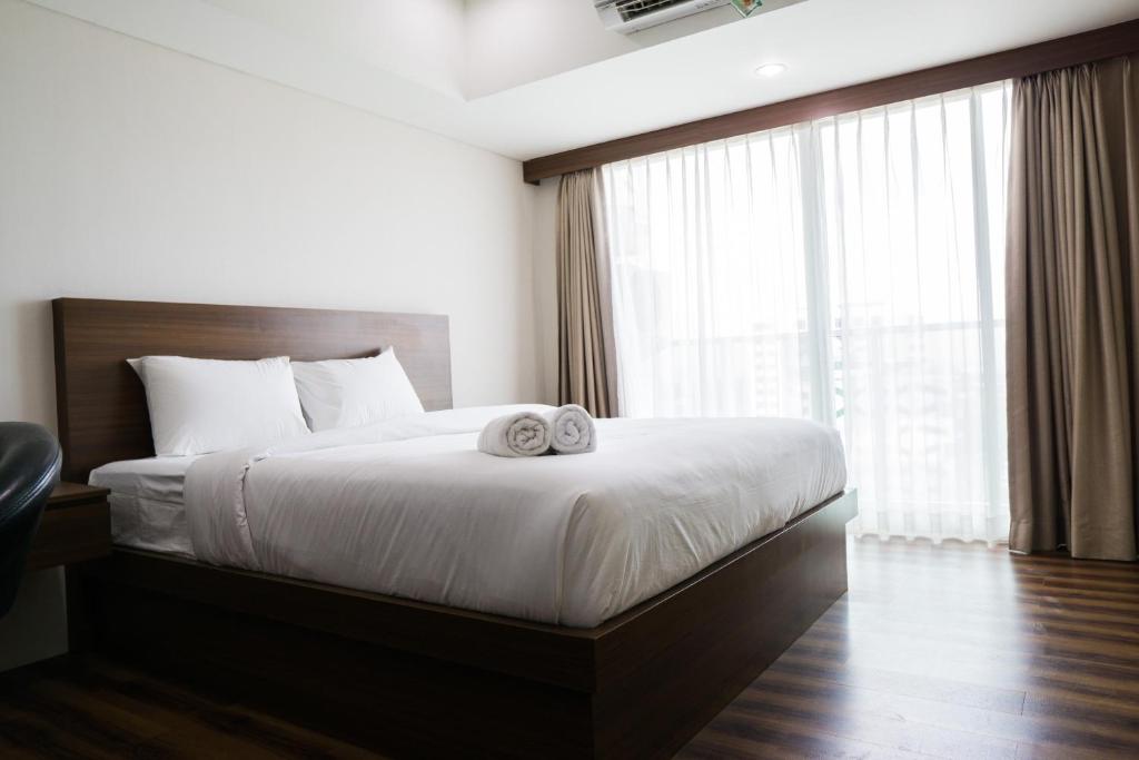a bedroom with a large bed with two towels on it at City View Studio Apartment at Tamansari La Grande By Travelio in Bandung