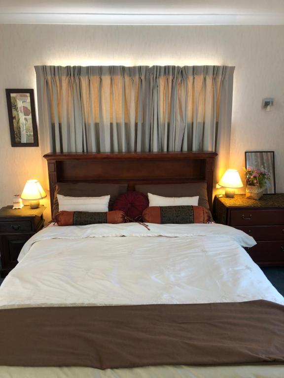 um quarto com uma grande cama branca e 2 candeeiros em A Cozy Room with It's Own Privacy em Upper Hutt