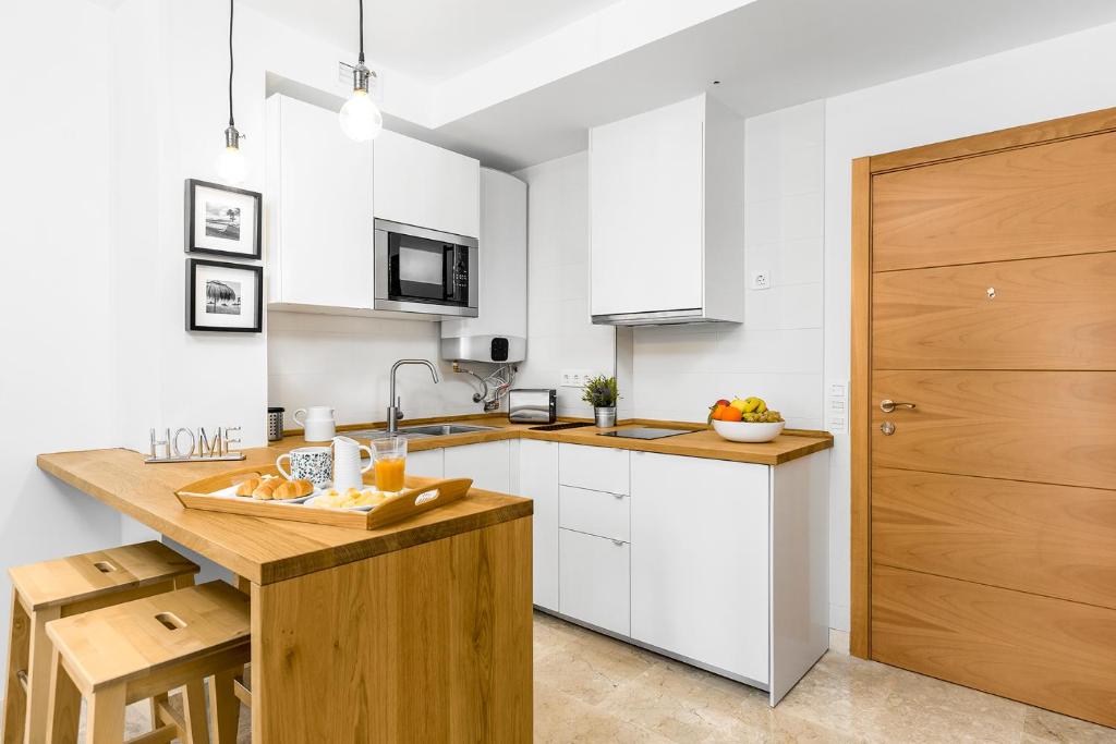 kuchnia z białymi szafkami i drewnianym blatem w obiekcie Apartamento Lujo Ancha del Carmen w Maladze
