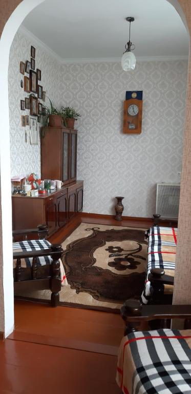 a living room with two beds and a clock on the wall at Nikoloz Guesthouse in Stepantsminda