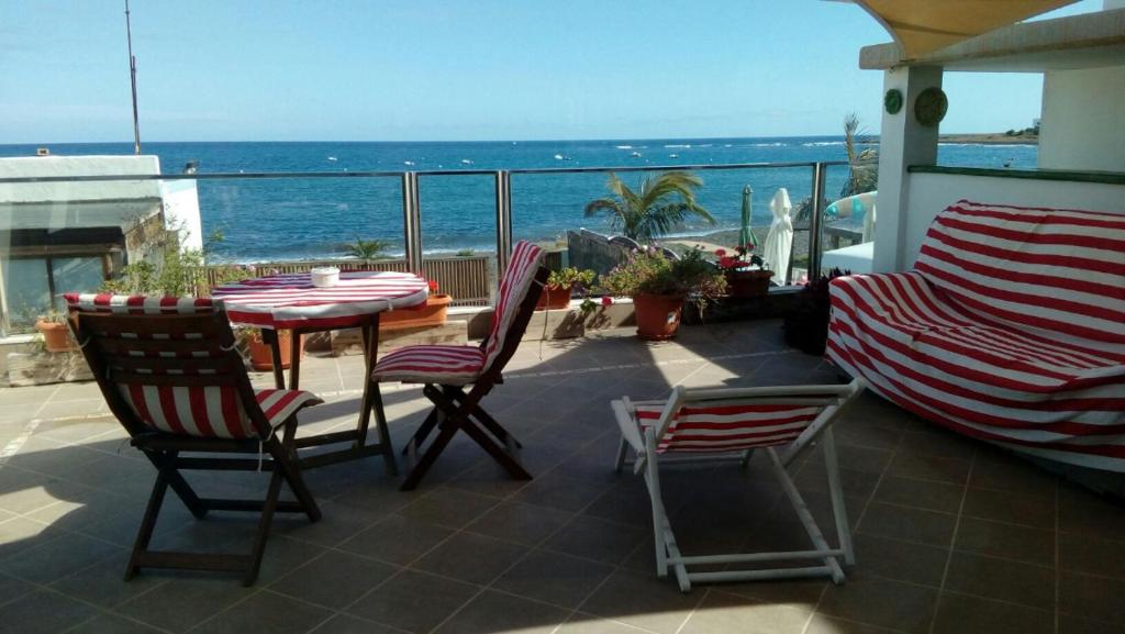 um pátio com uma mesa e cadeiras e o oceano em Apartamento con encanto en la playa frente al mar "Posada Rent House" em Puerto del Rosario