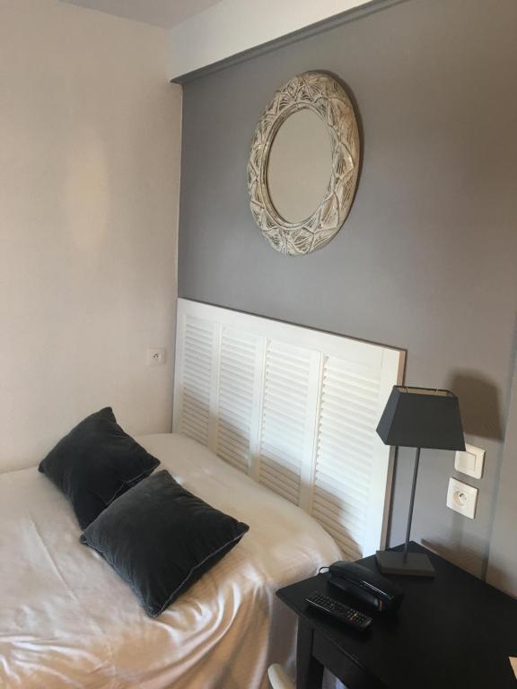 a bedroom with a bed and a mirror and a table at Hôtel Le Mistral in Marseille