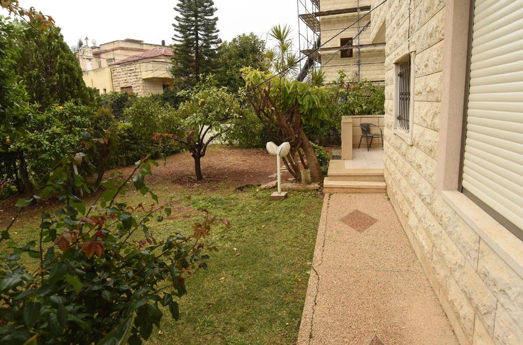 a yard with a garden with trees and a house at The Garden apartment in Nazareth