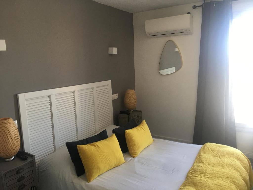 a bedroom with a white bed with yellow pillows at Hôtel Le Mistral in Marseille
