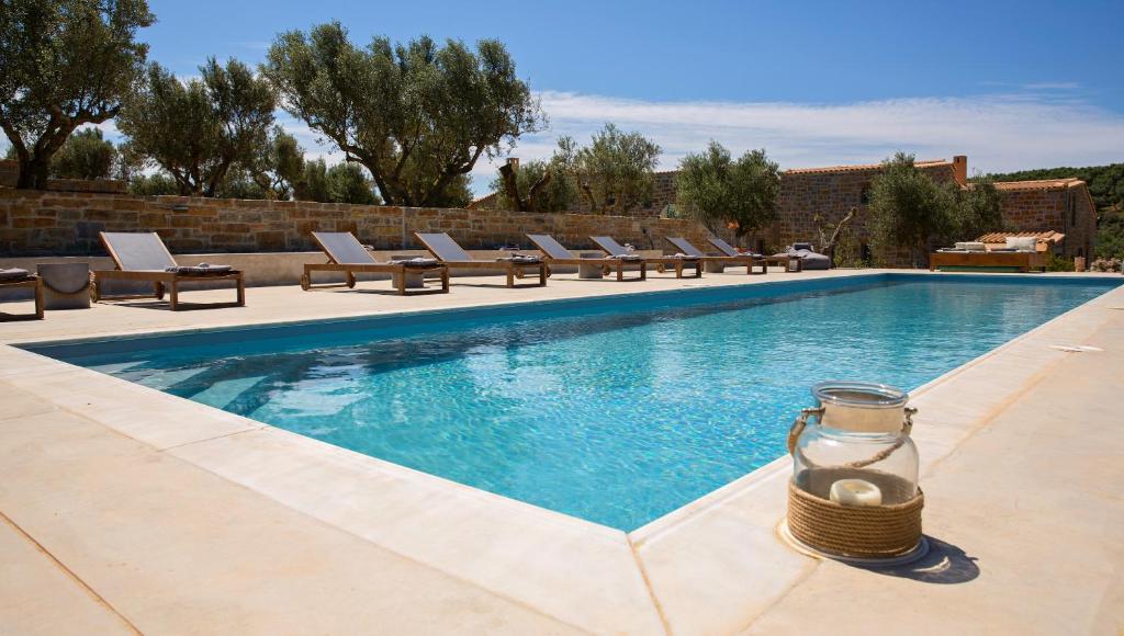 a swimming pool with lounge chairs and a jar next to it at Afentiko Pigadi in Methoni