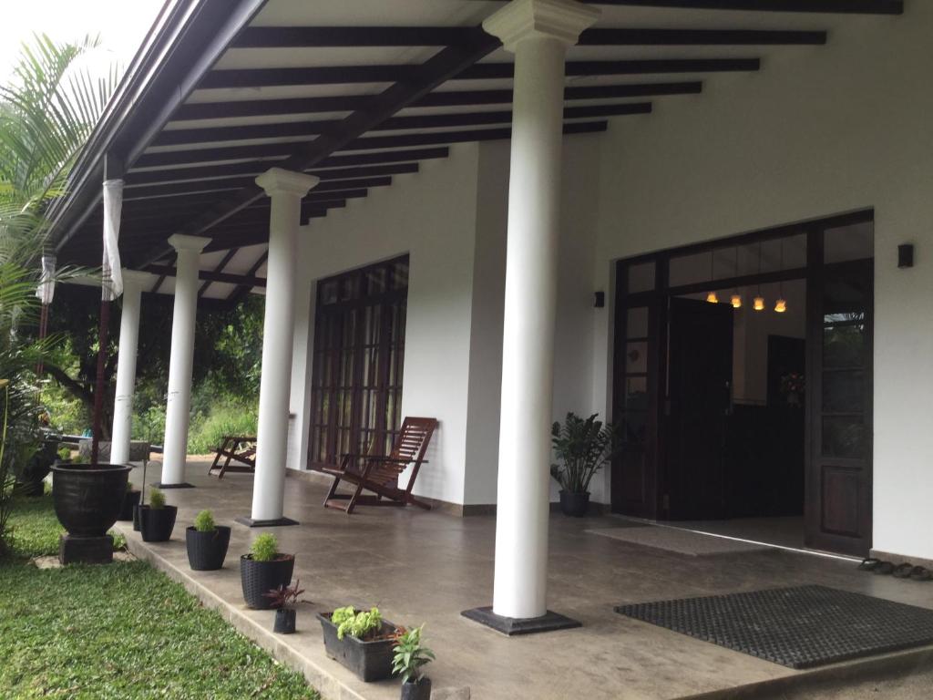 a porch of a house with columns and plants at Kandyan Lounge in Kiribatkumbura