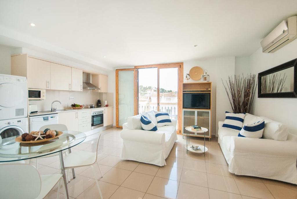 a living room with two white chairs and a glass table at Lets Holidays Estrella Pelegri 2 in Tossa de Mar