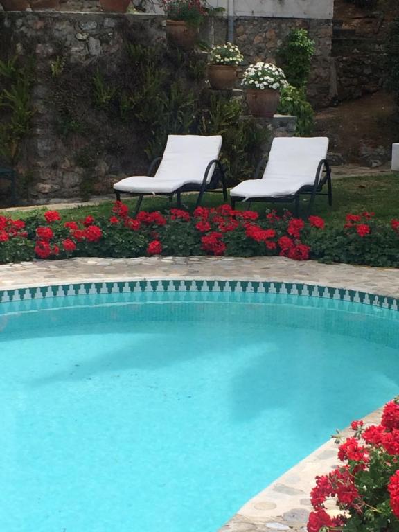 two chairs and a swimming pool with flowers at villaquinta in La Herradura
