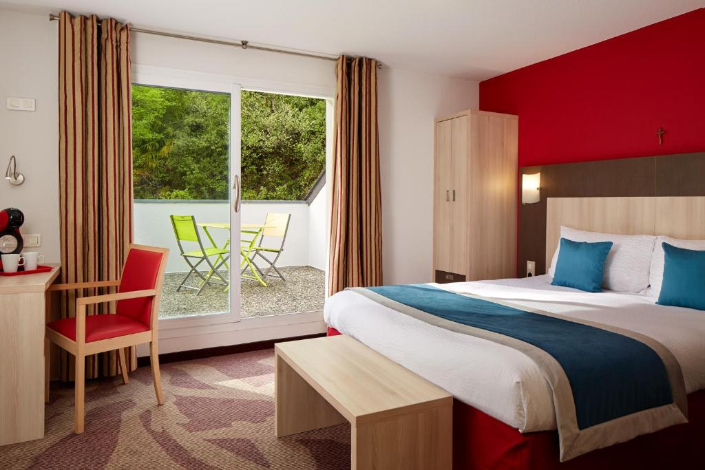 a hotel room with a bed and a window at H&ocirc;tel Roissy in Lourdes