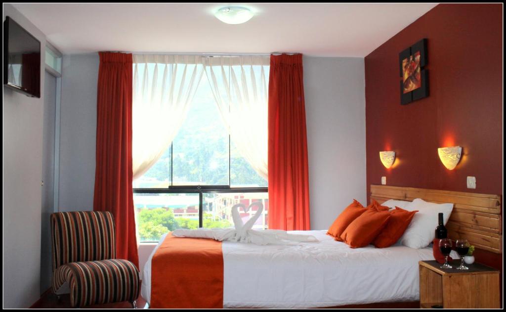 a bedroom with a bed with orange curtains and a window at El Peregrino Apart Hotel in Abancay