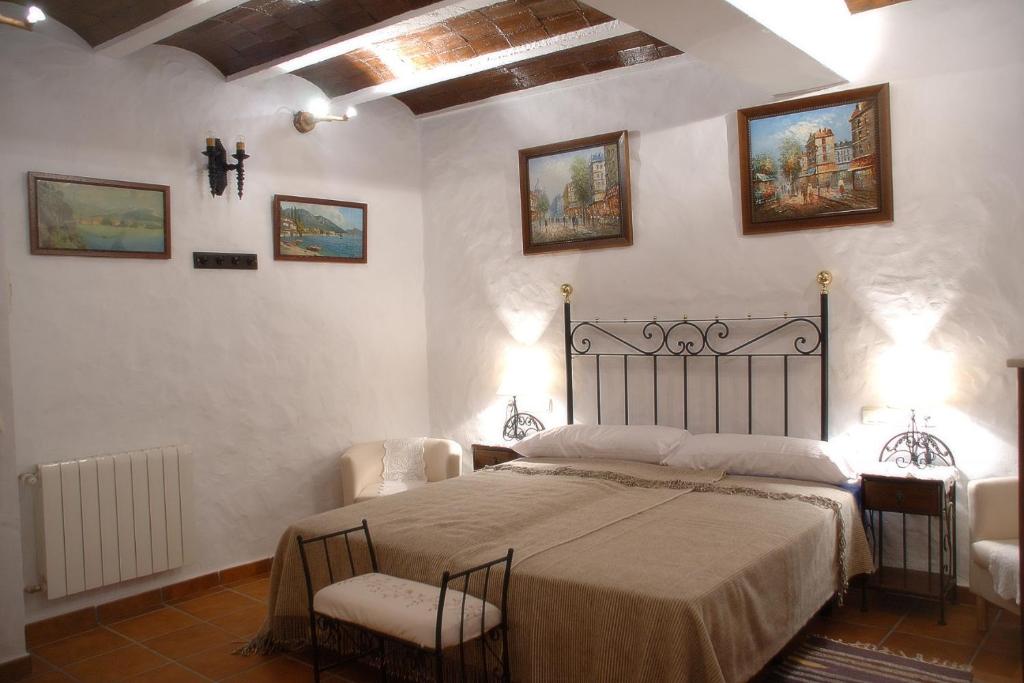 ein Schlafzimmer mit einem Bett mit 2 Stühlen und Gemälden an der Wand in der Unterkunft Guadalete in Grazalema