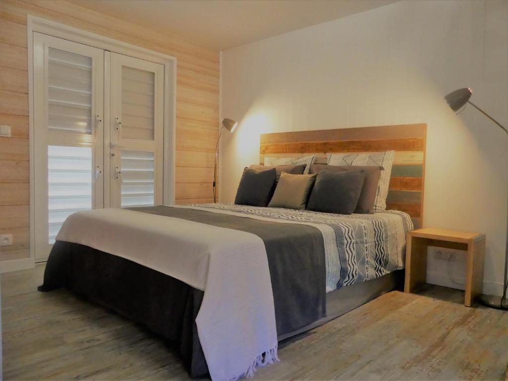 a bedroom with a large bed with a wooden headboard at Perle de Clugny in Sainte-Rose