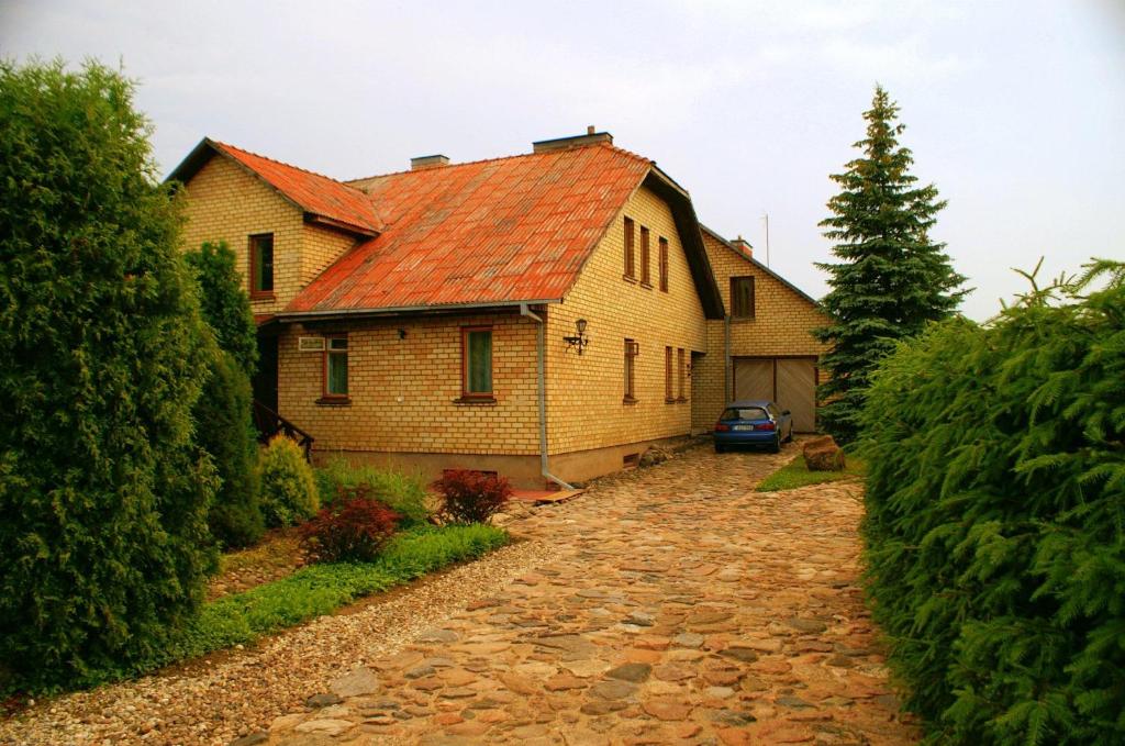 una casa con techo rojo y entrada de piedra en Prie upes en Kunioniai