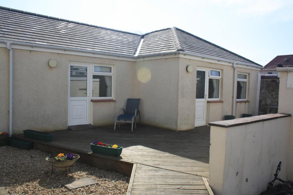 a house with a deck with a chair on it at Fairways Cottages in Prestwick