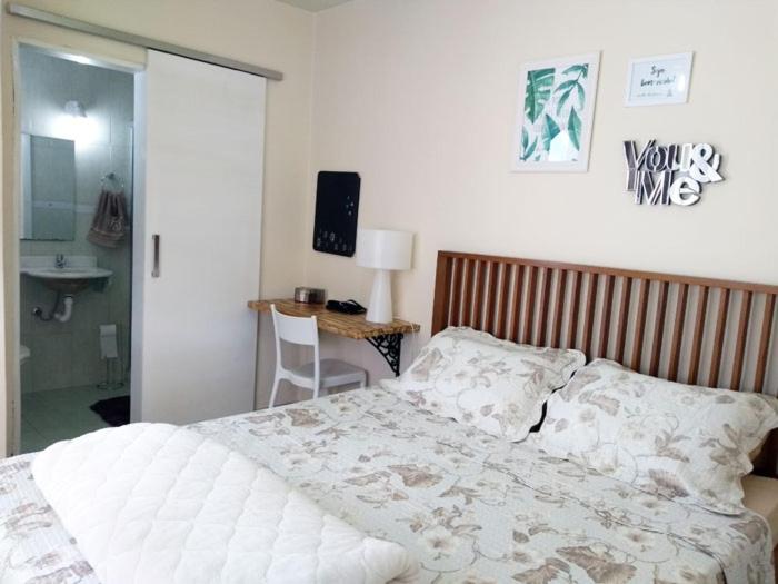 a bedroom with a bed and a desk with a television at Suíte da Fran - Perto da UFF in Niterói