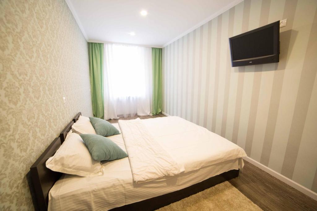 - une chambre avec un lit et une télévision murale dans l'établissement Staroievreiska Apartments, à Lviv
