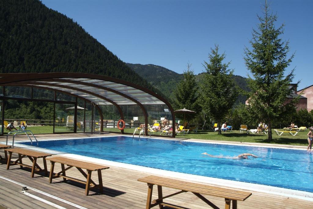 ein großer Pool mit Bänken und Menschen darin in der Unterkunft Hotel Montarto in Baqueira-Beret