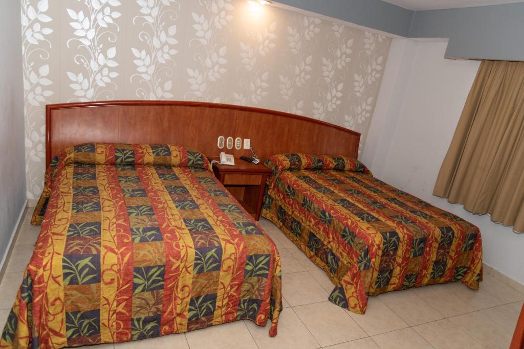 a hotel room with two beds and a table at Hotel Impala -Atras del ADO in Veracruz