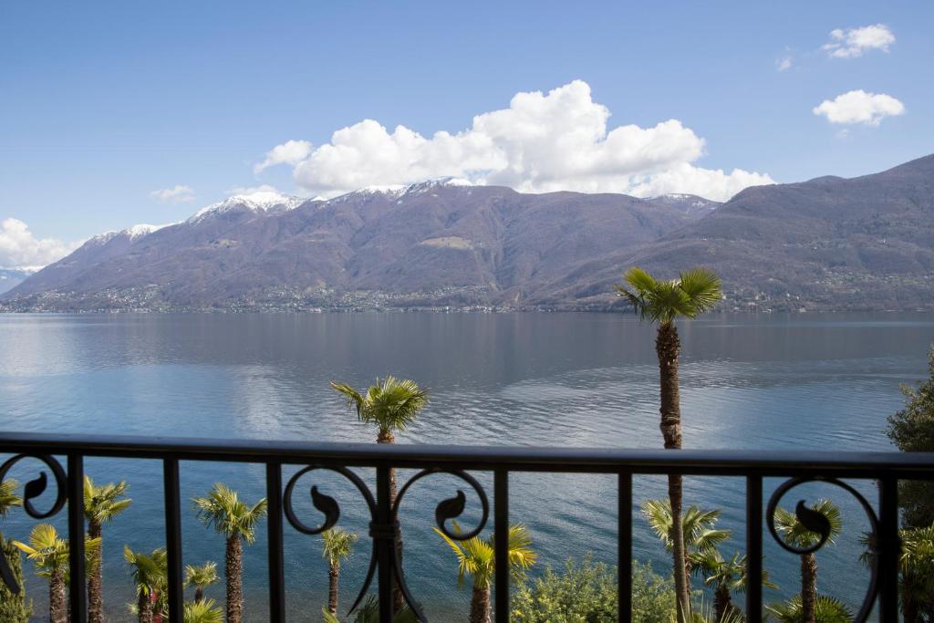 Elle offre une vue sur un lac avec des palmiers et des montagnes. dans l'établissement Hotel Garni Rivabella au Lac, à Brissago