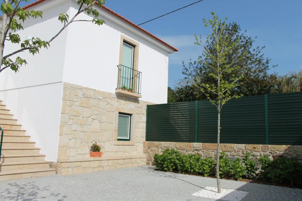 a white house with a fence and a tree at Casa da Rosa in Paredes de Coura