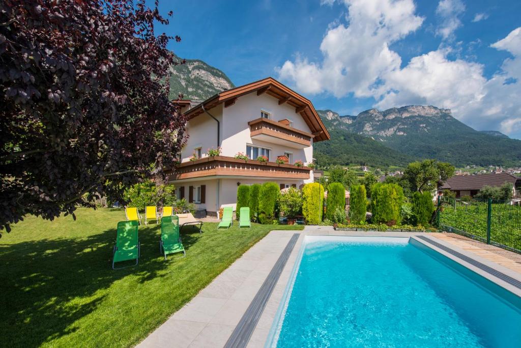 a villa with a swimming pool and a house at Gästehaus Thaler in Caldaro