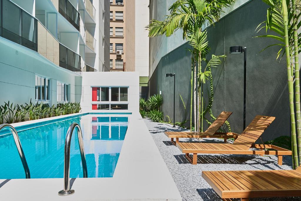 a pool with chairs and tables in it at Nomah - Aptos por Temporada na Luz in Sao Paulo