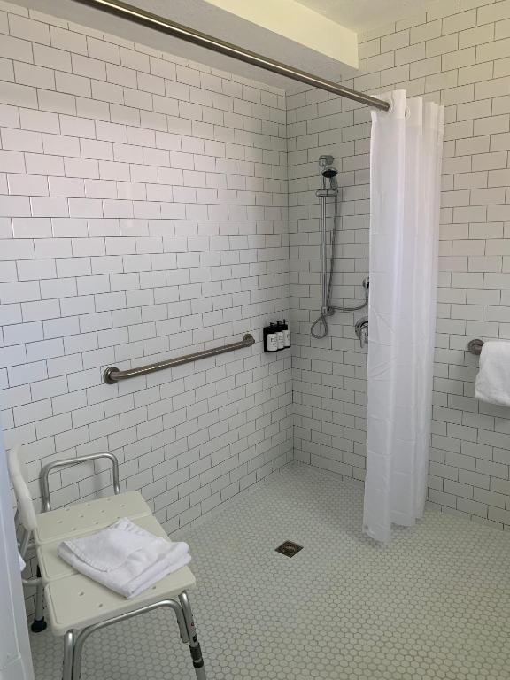 a white bathroom with a chair and a shower at Sunset Inn in Islamorada