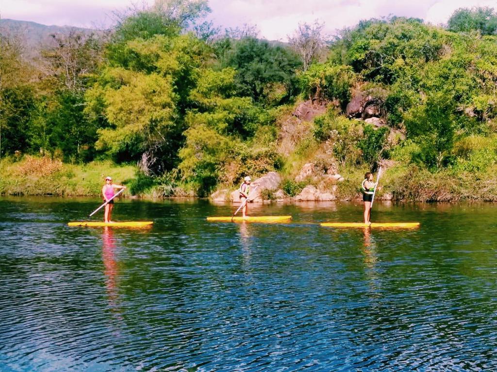 three people on paddle boards in the water at Hostel La Fortaleza in Bialet Massé
