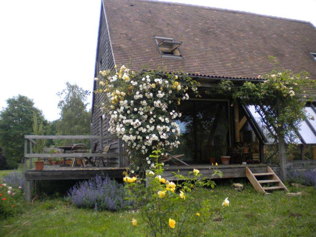 a house with a porch with flowers in the yard at Chambre d'Hôtes Douceurs Périgourdines in Marquay