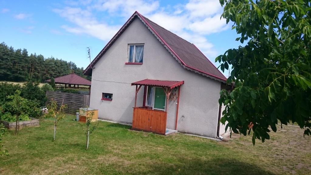 une petite maison blanche avec un toit rouge dans l'établissement Dom Bursztynek - domek (sad), à Junoszyno