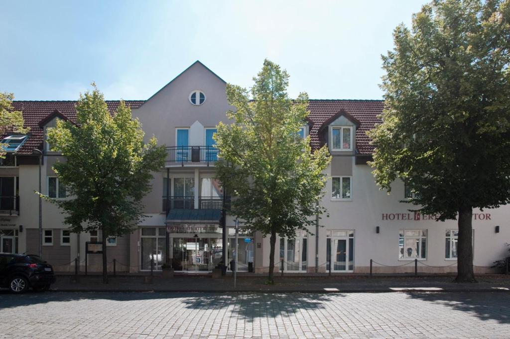 a large white building with trees in front of it at Hotel Erfurter Tor in Sömmerda