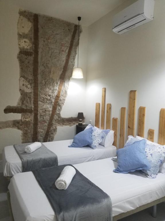2 camas en una habitación con una pared de piedra en Casa Lemus en Madrid