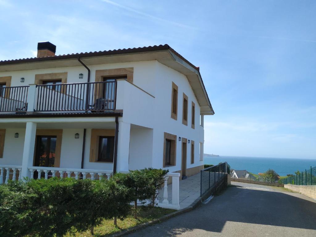 a white house with a balcony on the side of a road at El Ribero de Langre in Langre