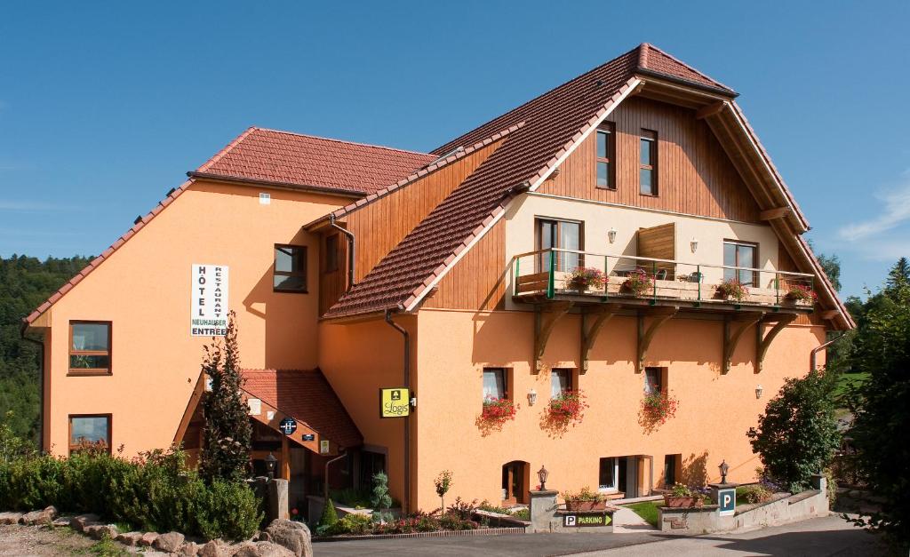 un grand bâtiment orange avec un toit marron dans l'établissement Hotel Neuhauser, à La Broque