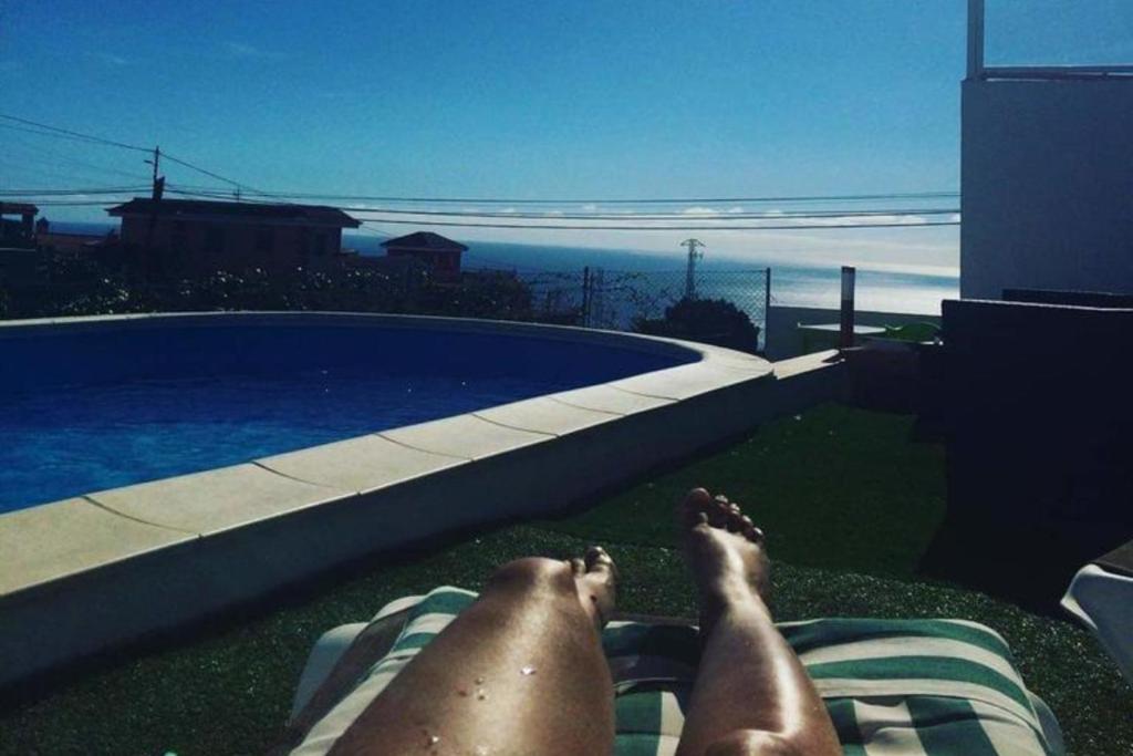 a person laying on the grass next to a swimming pool at modern holiday apartment with private pool in Adeje