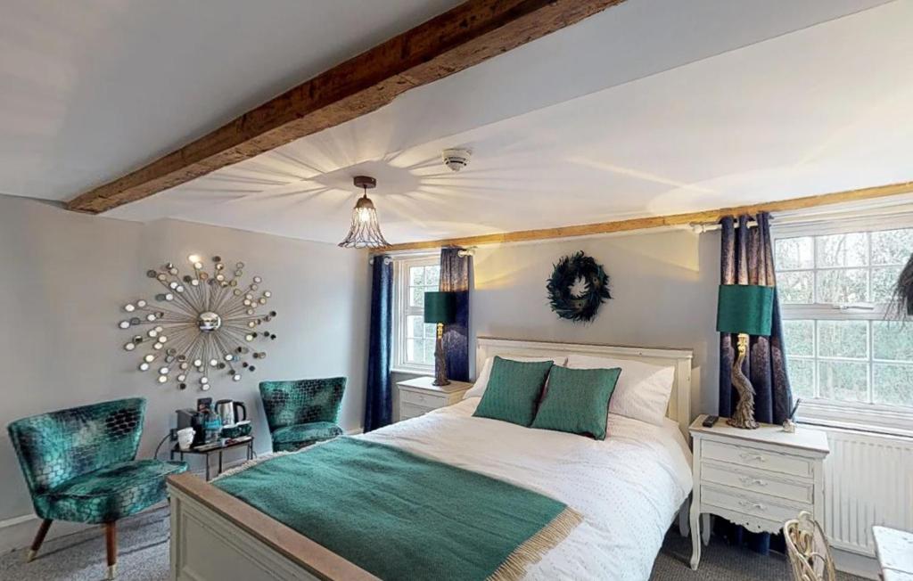 a bedroom with a large bed and green chairs at The Horse Inn Hurst in Hurstpierpoint