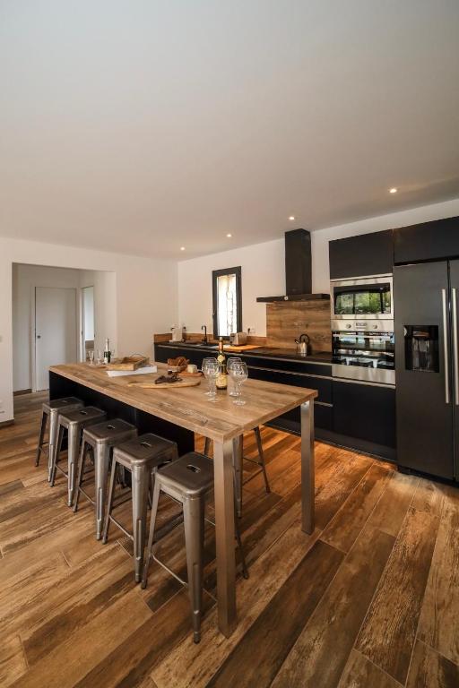 a large kitchen with a large wooden table and stools at Hôtel confidentiel Le Grecale in Pianottoli-Caldarello