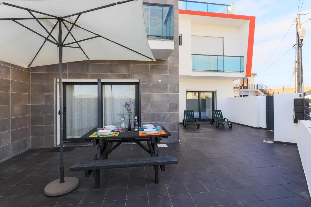 a patio with a table and an umbrella at Vitamin Sea, The Terrace Apartment in Baleal