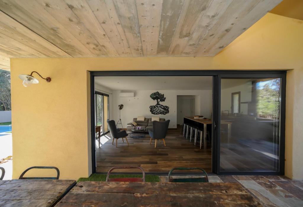 a dining room and living room with sliding glass doors at Hôtel confidentiel Le Grecale in Pianottoli-Caldarello