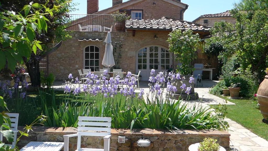 a garden with purple flowers in front of a house at Casa di Leo with pool in Radicondoli