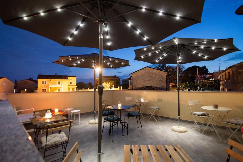 a patio with tables and chairs and umbrellas at Mama Residence in Rovinjsko Selo